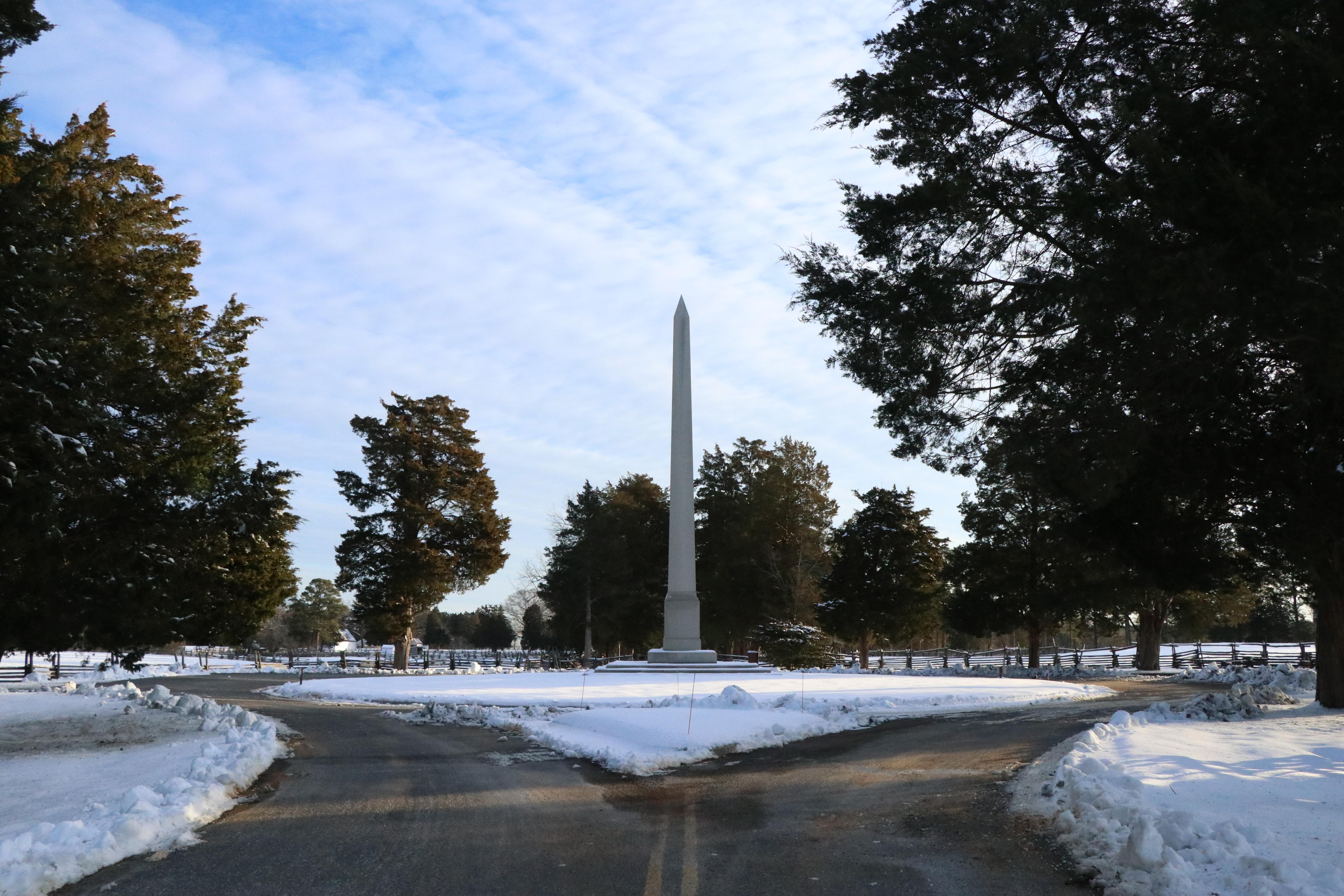 A large monument sits in the middle of a roundabout with snow on the ground