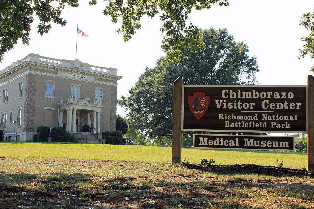 A two story gray brick building and a wooden sign reading "Chimborazo Visitor Center"
